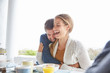 © Ryan Lees/Caia Image - Affectionate couple hugging and laughing at breakfast on patio