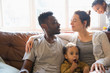 © Sam Edwards/Caia Image - Affectionate multi-ethnic young family on living room sofa
