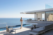 © Tom Merton/Caia Image - Woman on sunny modern, luxury home showcase exterior patio with ocean view