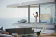 © Tom Merton/Caia Image - Woman with digital camera photographing ocean view on modern, luxury home showcase balcony