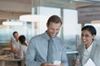 © Tom Merton/Caia Image - Businessman and businesswoman using cell phone in office