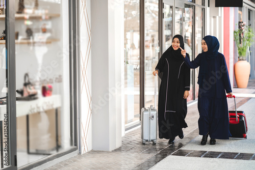 Fotomural Two young asian muslim woman enjoying shopping and having fun pointing finger in