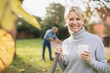 © Sam Edwards/Caia Image - Portrait smiling, confident mature woman drinking coffee and raking autumn leaves in backyard