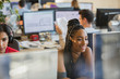 © Tom Merton/Caia Image - Smiling businesswoman with headset working at computer in office