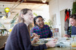 © Tom Merton/Caia Image - Happy young adult roommates eating take out food at kitchen table in apartment