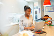 © Paul Bradbury/Caia Image - Boy playing next to mother working at laptop in kitchen