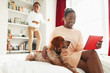 © Paul Bradbury/Caia Image - Boy jumping on bed behind dog and mother with digital tablet