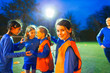 © Paul Bradbury/Caia Image - Portrait confident girl soccer player on field with team at night