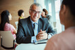 © Robert Daly/Caia Image - Smiling businessman listening to colleague in cafeteria