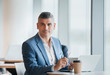 © Robert Daly/Caia Image - Portrait confident businessman working at laptop and drinking coffee
