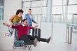 © Robert Daly/Caia Image - Playful couple running with luggage cart in airport