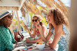 © Paul Bradbury/Caia Image - Happy women friends eating salad at sunny beach bar