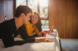 © Tom Merton/Caia Image - Smiling couple with headphones sharing digital tablet in bed