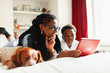 © Paul Bradbury/Caia Image - Grandmother and grandson using digital tablet next to sleeping dog on bed