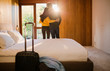 © Tom Merton/Caia Image - Couple with suitcase hugging in bedroom