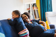 © Sam Edwards/Caia Image - Playful pregnant mother and daughter on sofa