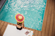 © Tom Merton/Caia Image - Woman in sun hat and bikini relaxing at poolside