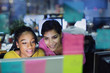 © Tom Merton/Caia Image - Smiling businesswomen working at computer behind adhesive notes