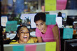 © Tom Merton/Caia Image - Happy businesswomen using computer behind adhesive notes in office