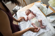 © Sam Edwards/Caia Image - Mother changing diaper of newborn baby son on changing table