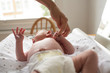 © Sam Edwards/Caia Image - Mother holding hands with newborn baby son laying on changing table