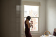 © Sam Edwards/Caia Image - Mother holding innocent newborn baby boy at window