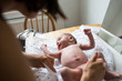 © Sam Edwards/Caia Image - Mother changing diaper of newborn baby son on changing table