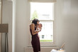© Sam Edwards/Caia Image - Mother kissing newborn baby son in window