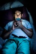 © Science RF - Man using smartphone in bed