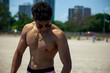 young middle eastern man with great abs and chest is walking across the sandy beach of Chicago shirtless.  wearing styling shades and athletic body he is having fun in the summertime