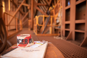 Wall Mural - danger tape, tags sign placing top of working at height permit booklet with defocused abseiler inspe