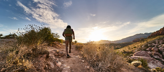 athletic african american woman hiking through red rock canyon in nevada at sunset