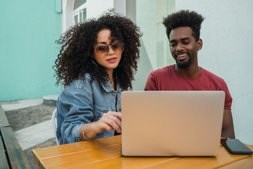 Two Afro friends using laptop at a cafeteria.