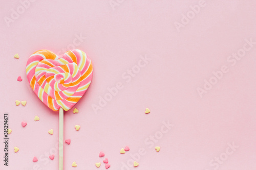 Big striped heart-shaped lollipop and confectionery confetti on a pink background copy space Tableau sur Toile