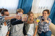 © carles - Group of young people toasting sitting on a sofa