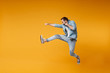 Side view of crazy young bearded man in casual blue shirt posing isolated on yellow orange background studio portrait. People sincere emotions lifestyle concept. Mock up copy space. Jumping, fighting.
