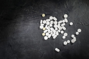 Heap of assorted various medicine tablets and pills on dark background