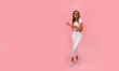 © ClaudiK - Image of happy young lady standing isolated over pink background. Looking camera pointing.Photo of happy young woman standing isolated over pink wall background, showing copyspace.