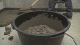 Fototapeta Pomosty - Black bucket with mortar for filling the floor. Bucket with mortar at the construction site.