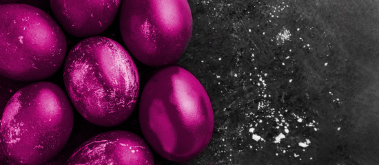  card with easter eggs painted in fluorescent glowing purple color on black background with white crumbs, egg shell with white stains, scuffs, scratches. handmade painted eggs. Flat lay with copy space