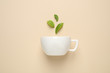 Fresh tea leaves and cup on beige background, top view