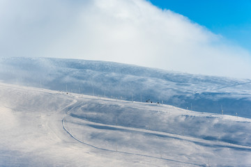 Wall Mural - ski slopes on a snow covered mountain with no trees or vegetation and almost no people under a blue 