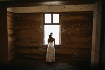 Poster - bride looking through window of old desert house on her wedding day