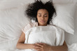 © fizkes - African woman sleeping in bed close up top view