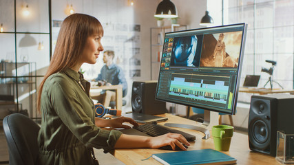 Wall Mural - beautiful brunette female video editor works with footage on her personal computer with big display.