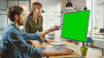 Wall Mural - female art director consults designer colleague, they work on a personal computer with green screen 