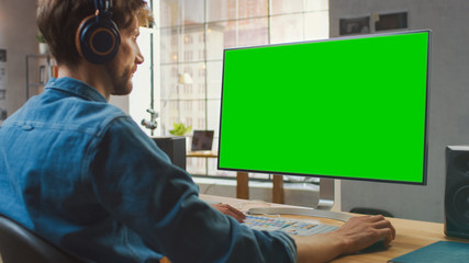 Wall Mural - young professional creative employee works on his personal computer with big green screen mock up di
