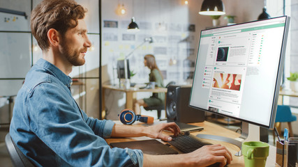 Wall Mural - beautiful male scrolls through social media site on his personal computer with big display. he works