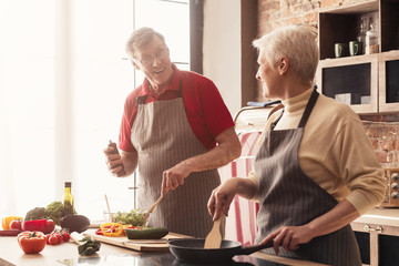 Wall Mural - Senior husband and wife cooking dinner at kitchen together