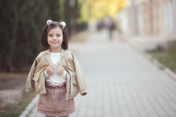 Wall Mural - Smiling child girl 3-4 year old walking on street wearing spring clothes outdoors. Looking at camera. Childhood.